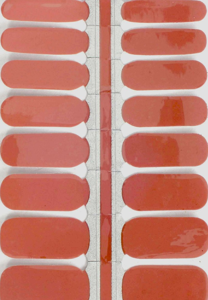 Set von rechteckigen Nagellackstreifen in verschiedenen Schattierungen von Korallenrosa, mit glänzender Oberfläche, glatter Textur und weißem Kleberücken.