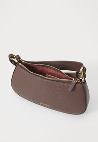 Brown leather handbag with a textured finish, gold hardware, and a zip closure. Includes a deep red interior and adjustable strap.