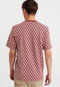 Kortärmad skjorta i ett röd- och krämfärgat geometriskt mönster, gjord av mjukt tyg, med rundad halsringning och avslappnad passform.