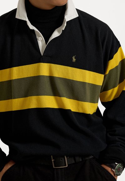 Μαύρο μακρυμάνικο πουκάμισο πόλο με άσπρο γιακά, με οριζόντιες ρίγες σε κίτρινο και ελαιόλαδο, και ένα μικρό λογότυπο στο στήθος.