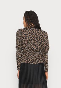Blusa preta com padrão floral em cores suaves; apresenta mangas bufantes e um design de cintura franzida. Tecido suave com uma textura lisa.