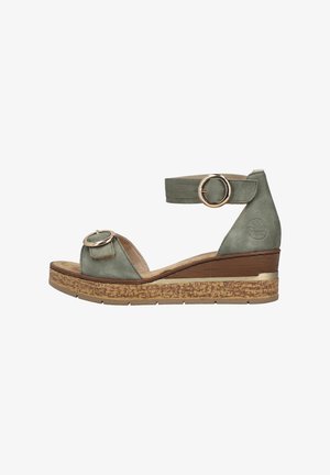 Grüne Wildleder-Wedgesandalette mit Korksohle, offener Zehenpartie, verstellbarem Knöchelriemen und runden Metallelementen auf der Vorderseite.