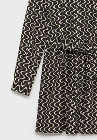 Robe noire à manches longues avec des rayures ondulées beige, boutonnée sur le devant, ceinture assortie en tissu nouée à la taille et manches à revers.