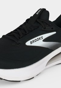 Black Brooks running shoe with white and silver logo on side and "Revel 9" text on tongue, showing laces and sole details.
