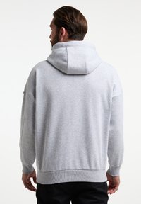Hanorac cu glugă de culoare gri deschis, cu o textură moale, croială lejeră, mansete ribbate și o glugă groasă, fără logo-uri sau accente vizibile.