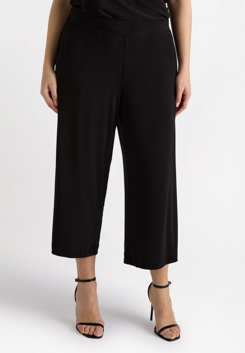 Pantalons noirs cropped en tissu léger avec une texture lisse. Ils présentent une taille large et une coupe ample et fluide.