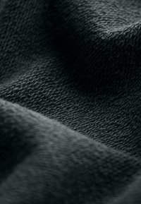 Tessuto nero texture che mostra una superficie morbida e intrecciata con una leggera lucentezza, caratterizzato da una combinazione di motivi lisci e in rilievo.