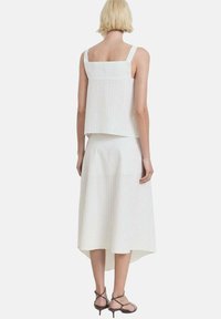 Conjunto de dos piezas a rayas blancas que incluye una blusa sin mangas de corte cuadrado y una falda midi fluida. Incluye tirantes finos.