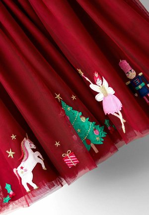 Roter Stoff mit gestickten Weihnachtsmotiven, darunter ein Einhorn, ein Geschenk, ein Baum, eine Fee und ein Spielzeugsoldat.