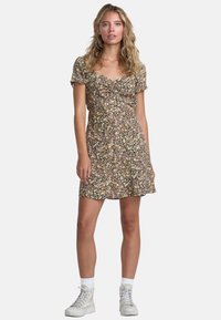 Zwart bloemenprint jurk met korte pofmouwen, gerimpelde voorkant en een uitlopende zoom. Gestyled met witte sneakers en enkelsokken.