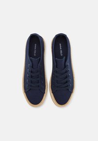 Navy canvas sneakers with six eyelet lacing system, round toe, and jute-wrapped sole. Textured material with stitched detailing.