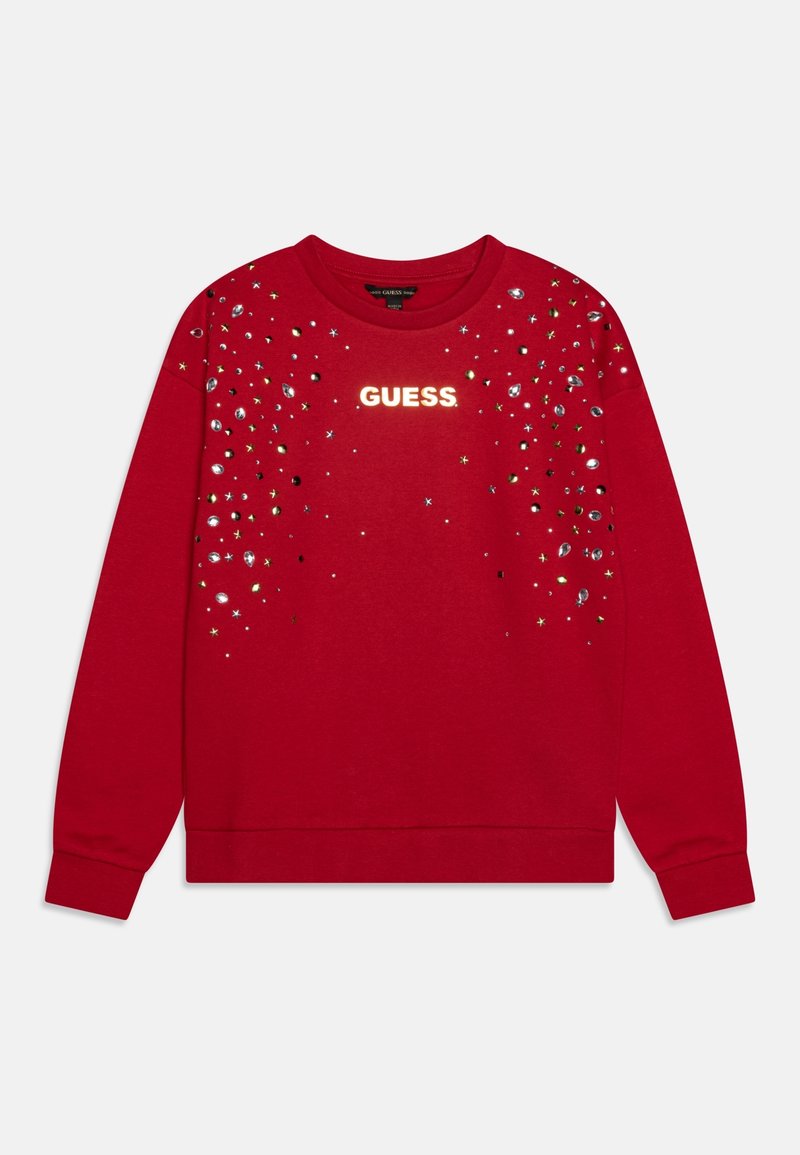 Pull rouge à manches longues avec logo "GUESS" au centre et embellissements d'étoiles et de pierres argentées et dorées dispersés sur le haut devant.