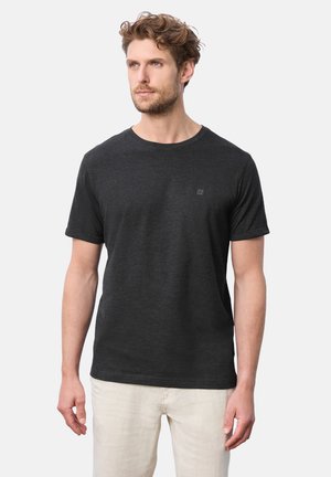 Kortærmet sort T-shirt lavet af blødt stof, med rund hals og lille logo-detalje på brystet, parret med lyse bukser.