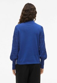 Blauer Pullover mit einem einfarbigen Körper und strukturierten, gemusterten Ballonärmeln. Gerippte Bündchen und Kragen unterstreichen das Design.