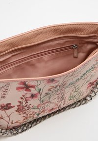 Torebka w kwiatowy wzór z różowym materiałem na zewnątrz, metalowym łańcuszkiem oraz gładkim satynowym wykończeniem wewnętrznym z kieszenią na zamek.