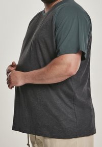 Koszulka z krótkim rękawem i okrągłym dekoltem, ciemnoszara z turkusowymi rękawami. Wykonana z miękkiego materiału, o luźnym kroju i ze szwem bocznym.