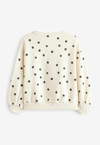 Sweat-shirt couleur crème à pois noirs, manches longues, poignets et ourlet côtelés, vu de dos sur un fond blanc.