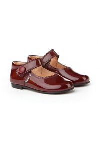 Zapatos Mary Jane de charol burdeos con bordes festoneados, correa ajustable y suelas planas. Textura suave con acentos decorativos de botón.