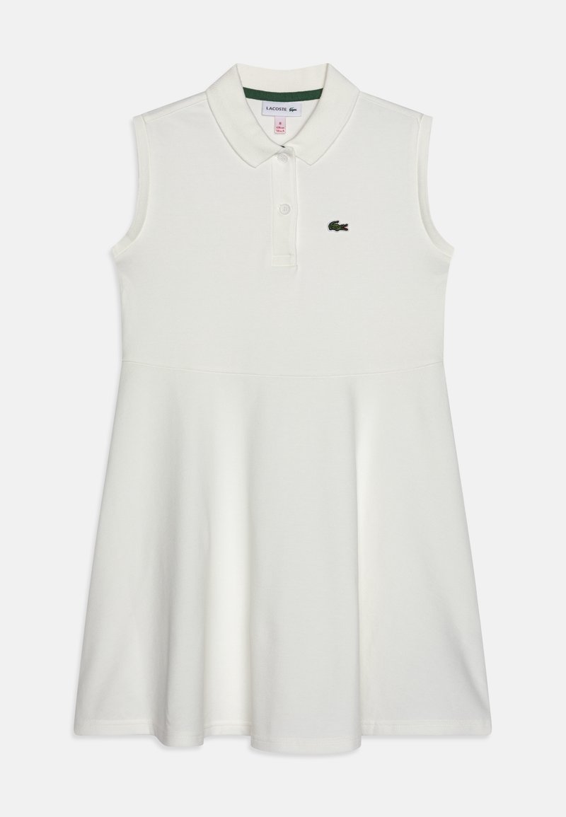 Robe polo blanche sans manches avec col, patte à deux boutons et petit logo crocodile vert sur la poitrine gauche.