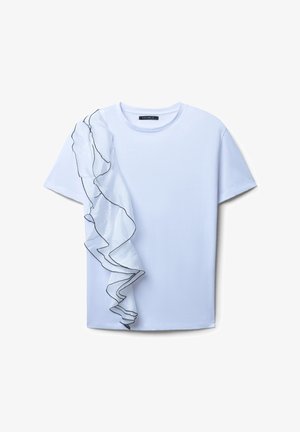 T-shirt blanc avec une seule manche en tulle froncé bordée de noir, présentant un col rond et des manches courtes, texture douce.