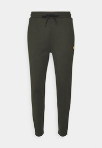 Olijfgroene joggers met een tailleband met trekkoord, taps toelopende pijpen, omgeslagen enkels en een klein geel logo op de dij. Zachte stoftextuur.