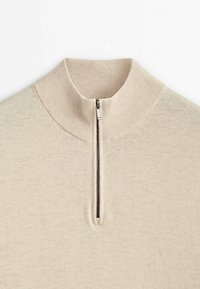 Beige knit sweater with a ribbed high collar and a centered half-zipper closure.