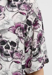 Țesătură cu model floral și de craniu, prezentând nuanțe de violet, gri și alb. Designul include cranii detaliate împletite cu flori.
