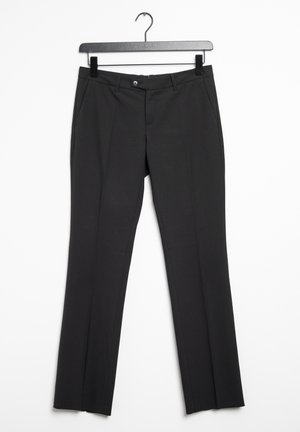 Pantalones de vestir negros de pierna recta con aberturas para cinturón, cierre frontal con botón y bolsillos laterales colgados en una percha negra sobre un fondo blanco.