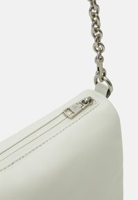 Borsa in finta pelle bianca con zip argentata e tracolla a catena. Presenta una texture liscia e una forma angolare, evidenziando il dettaglio hardware della zip.