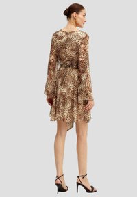 Abito in stampa leopardata con maniche lunghe, vita arricciata e orlo svasato. Tessuto leggero e trasparente in toni beige. Tacchi neri con cinturini.