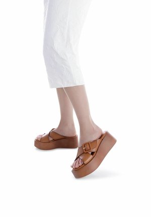 Sandali platform marroni con una larga fascetta e dettaglio con fibbia. Realizzati in pelle liscia, con una suola spessa e sagomata per un'altezza maggiore.