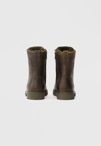 Botas de tornozelo em pele castanha com forro de pele e fecho de zip lateral; solas de borracha; costuras decorativas e logotipo discreto na parte de trás.