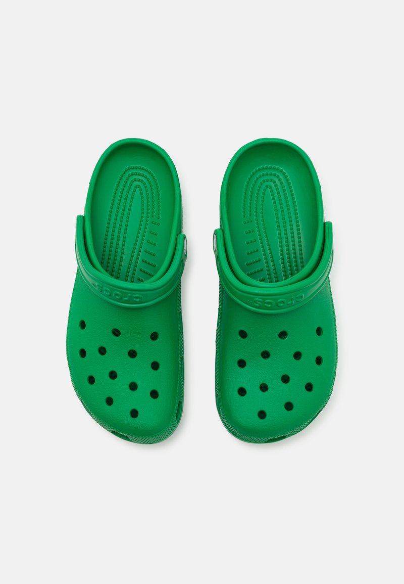 Zuecos de goma verdes con un diseño perforado, correa ajustable en el talón y plantilla texturizada para proporcionar tracción y comodidad.