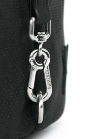 Sac noir avec une surface texturée, des accessoires en métal argenté et un grand clip en carabine attaché pour le fixation.