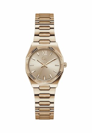 Kullatooni käekell tekstuurse sihverplaadi, Rooma numbriga XII, pulgakujuliste tunniindeksite, kolme osutiga ja metallist lingitud rihmaga.