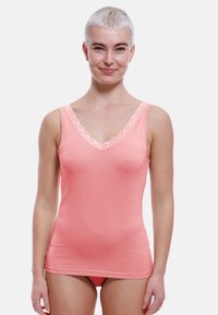 Peach tank top with a V-neckline and delicate lace trim at the edges. Made from smooth, stretchy fabric, fitted design.