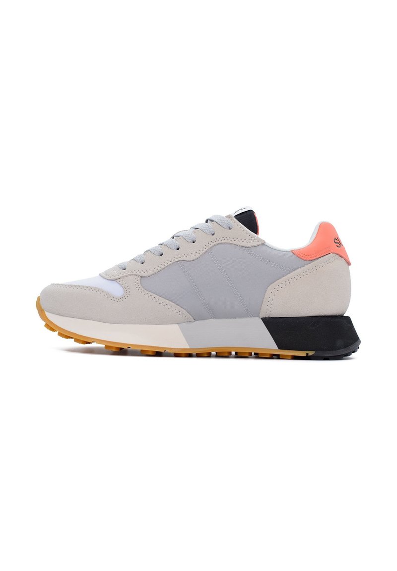 Zapato deportivo con un diseño en gris claro y negro, que cuenta con una parte superior de ante y sintético, cordones redondos y una suela de goma texturizada en amarillo.