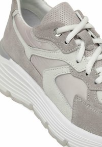 Light gray sneaker featuring a mix of suede and textile materials, a thick white rubber sole, and perforated detailing on the tongue.