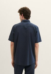 Short-sleeve navy shirt featuring a repeating geometric pattern, made of lightweight fabric with a relaxed fit and a standard collar.