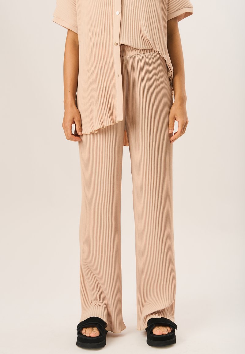 Beige ribbed knit two-piece set featuring a loose button-up shirt and elasticated waist pants. The fabric has a soft texture with subtle horizontal lines.