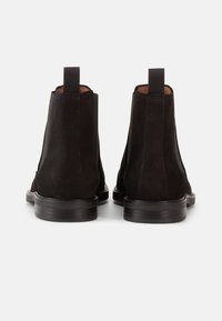 Μαύρα σουέτ μποτάκια Chelsea με ελαστικές πλαϊνές φάσες, λουράκι στο πίσω μέρος και λεπτές λαστιχένιες σόλες. Ομαλή υφή και  κλασικός σχεδιασμός αστραγάλου.