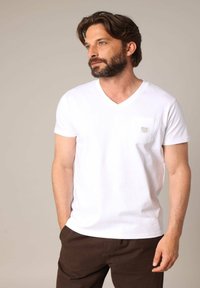 Witte katoenen V-hals T-shirt met korte mouwen, voorzien van een klein zakje aan de linkerkant van de borst en een gladde textuur.