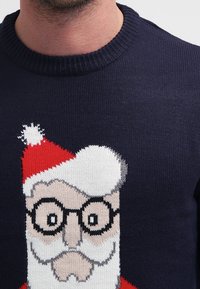 Granatowy sweter dziergany z wzorem Świętego Mikołaja w okularach, czerwonym kapeluszu i białej brodzie. Miękka tekstura, fason z okrągłym dekoltem.