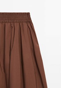Brown skirt with an elastic waistband, featuring gathered fabric for texture and a flowing design. Smooth surface with vertical seams.