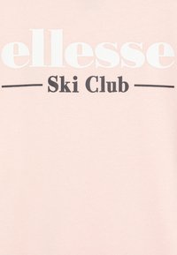 Sudadera rosa claro con "ellesse" en blanco y "Ski Club" en texto negro. Tejido suave, cuello redondo, diseño simple, sin patrones.