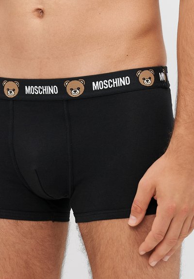Boxer brief in cotone nero con grafica di un orso e branding "Moschino" sulla cintura elastica. Presenta un design aderente e una texture liscia.