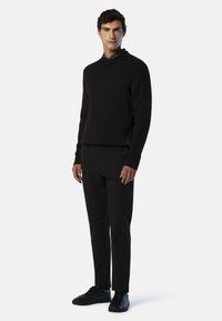 Maglione nero a maglia con collo alto, maniche a coste, abbinato a pantaloni neri a sigaretta e sneaker nere. Design semplice e monocolore.