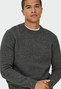 Szary sweter dzianinowy z okrągłym dekoltem, teksturowana tkanina, ściągacze przy rękawach i dopasowany krój. Minimalistyczny design, odpowiedni do noszenia na co dzień.
