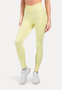 Lichtgele leggings met hoge taille gemaakt van rekbaar materiaal, met een gladde textuur en een wit logo op de tailleband.