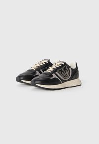 Zwarte leren sneakers met crèmekleurige accenten, voorzien van textuurpatronen en logo-details, ronde vorm en een gestructureerde rubberen zool.